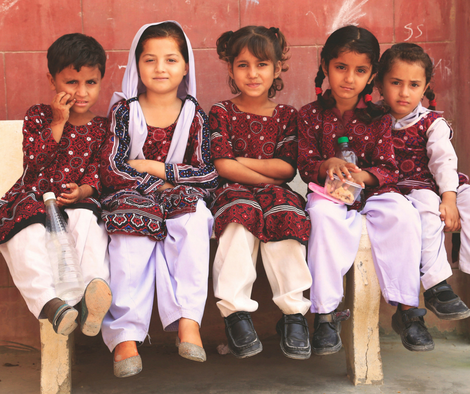 Young children sat together on bench, Pakistan