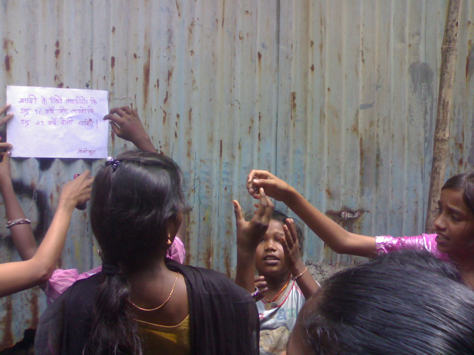 Girls putting up poster, India 