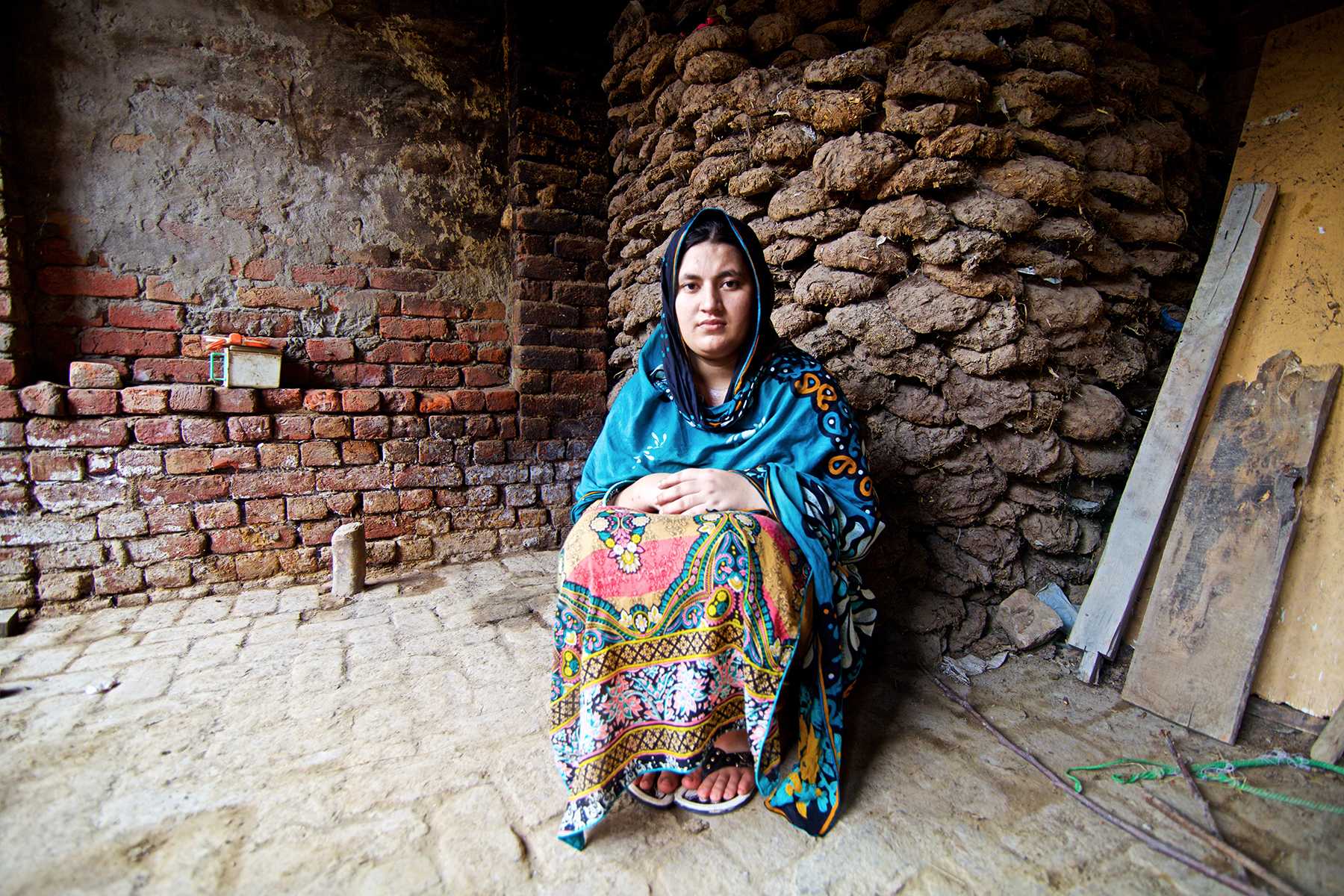 Woman sitting on the ground next to stone walls