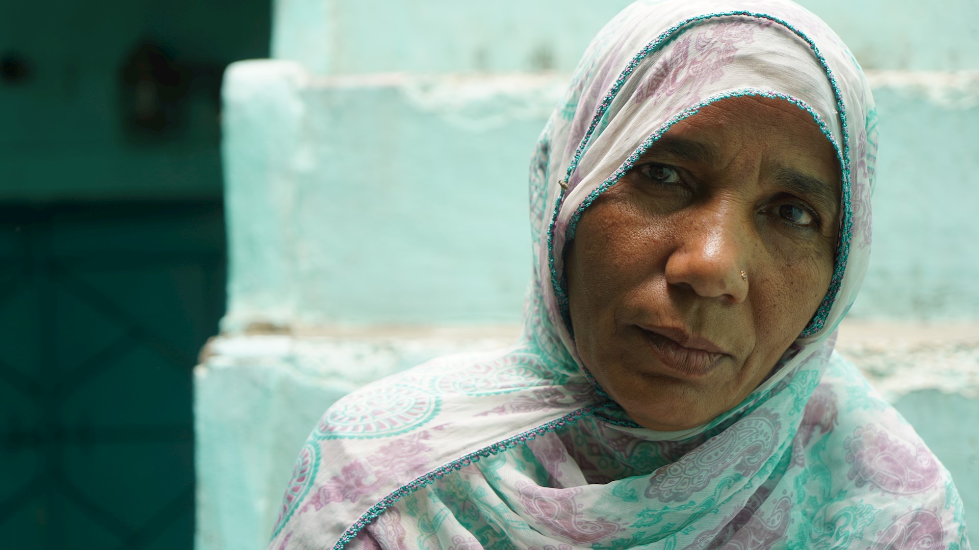 Lady in front of mint staircase staring into camera, Pakistan