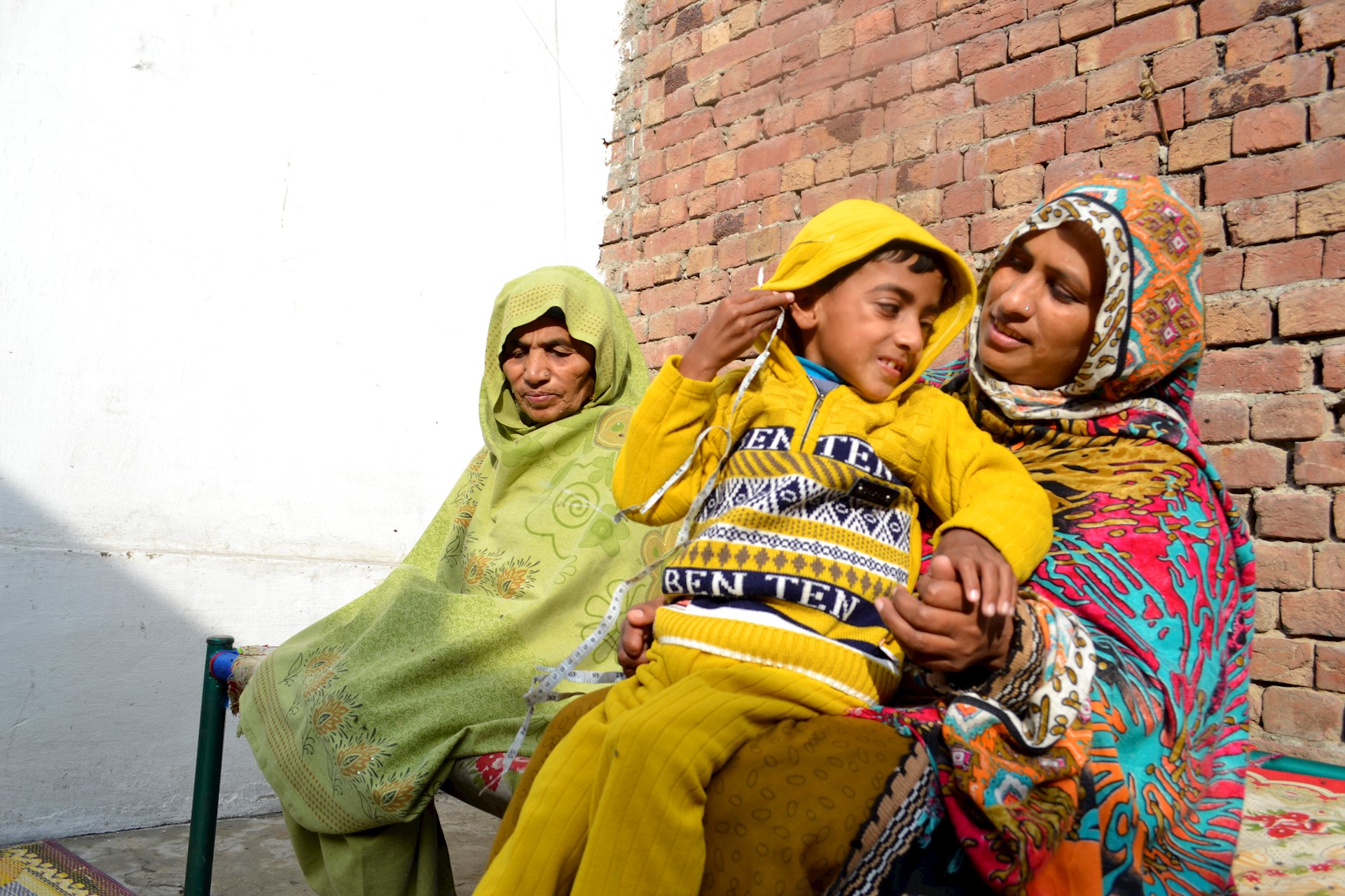 two women sat outside with young boy 