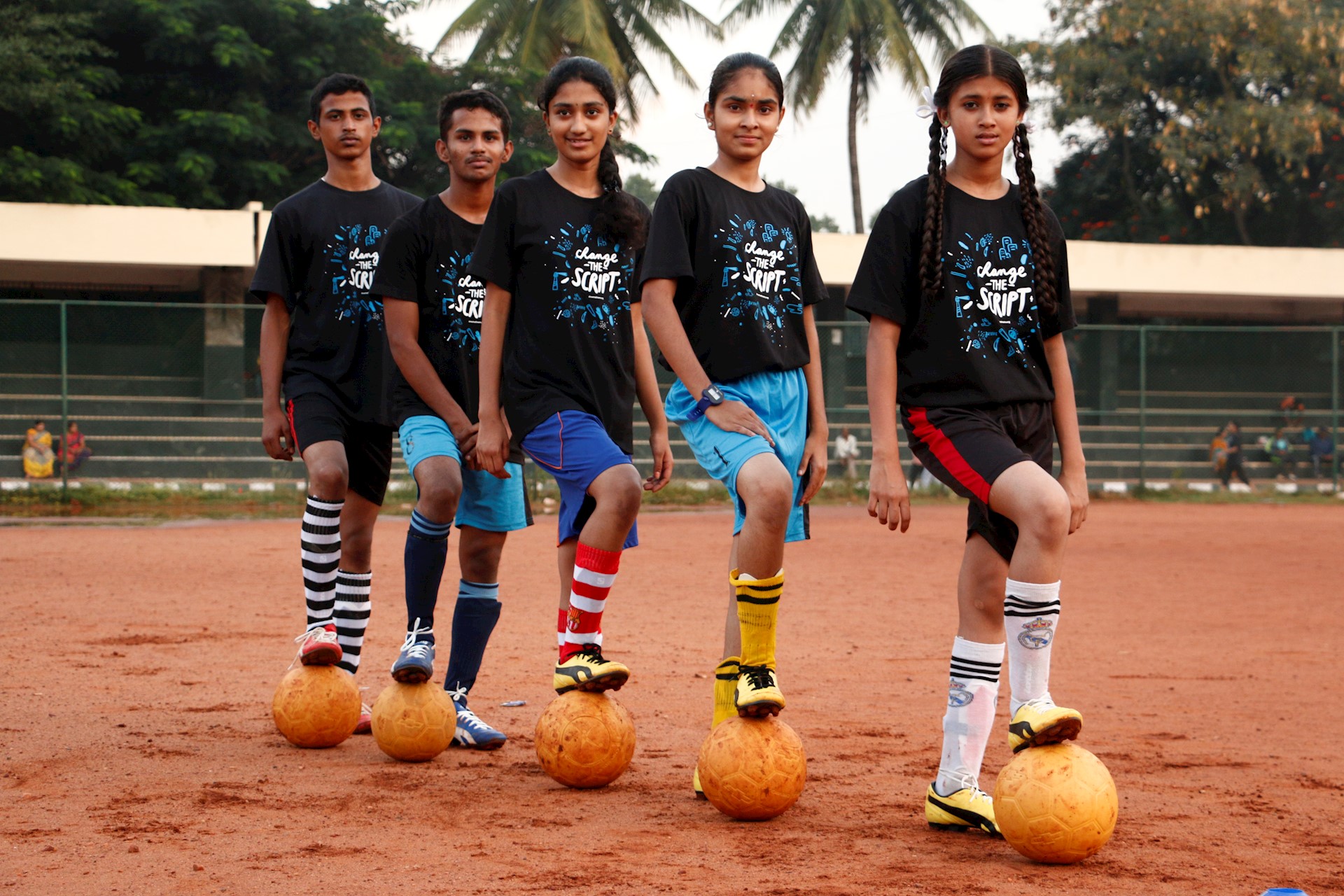 3 girls and 2 boys posing with footballs 