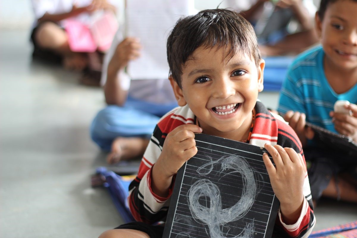 young boy holding chalkboard smiling to camera 