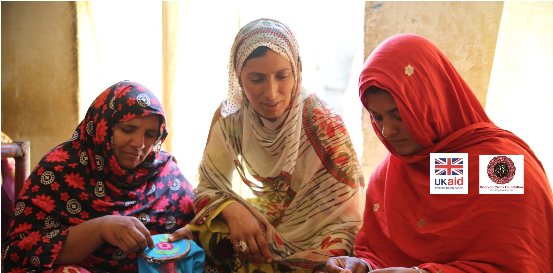 two women showing another woman to cross-stitch