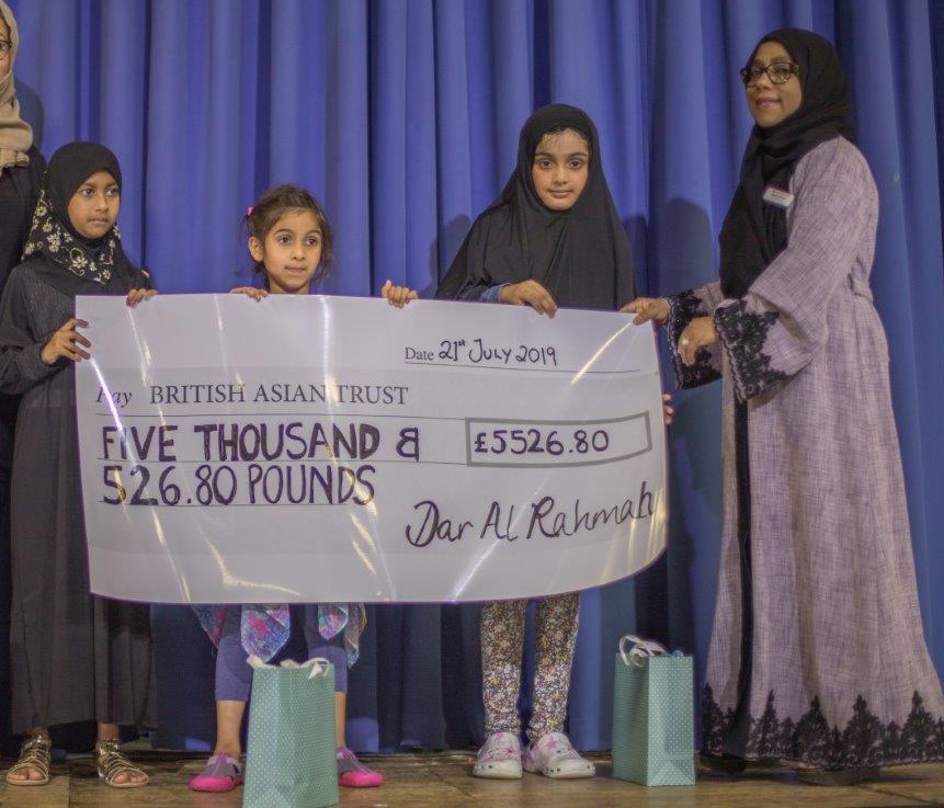 Children at school presenting large cheque after fundraising 