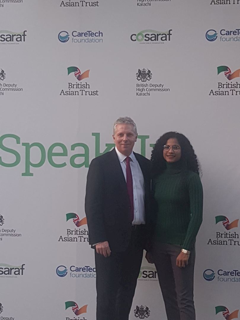 British Asian Trust CEO Richard Hawkes and Ambassador Hajra Khan being photographed in front of media board 